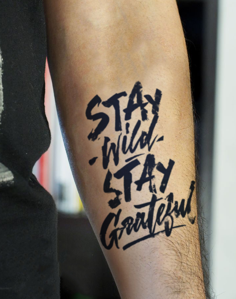 Temporary tattoo design on arm featuring the phrase 'Stay Wild, Stay Grateful' in bold lettering.